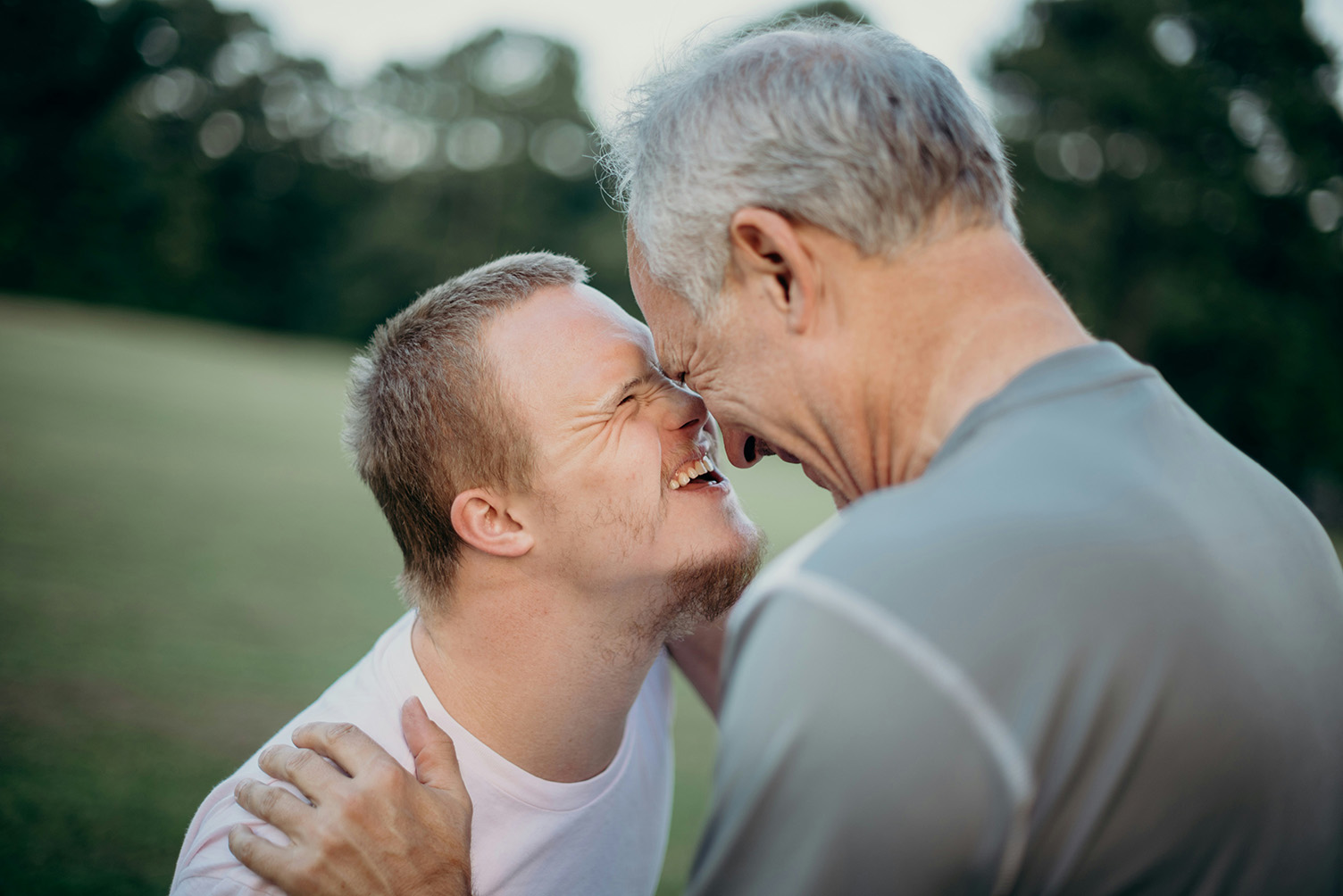 man with down syndrome smiles and touches foreheads with his father 