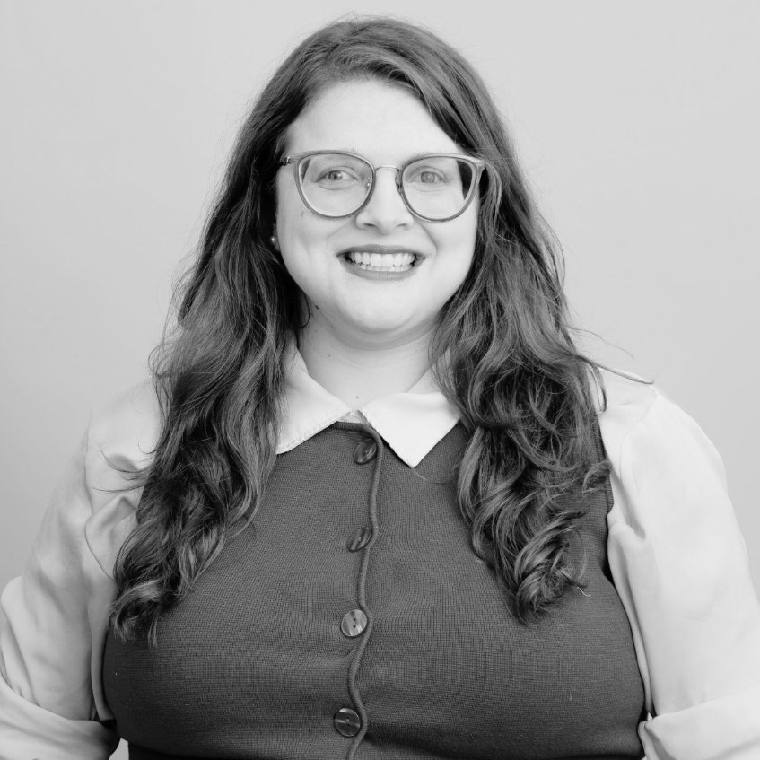 image of jess watkin smiling on a studio backdrop. she smiles and wears glasses.